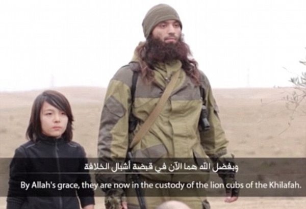 Un enfant irakien se tient à côté d'un soldat de l'Etat Islamique et est a priori sur le point d'assassiner deux espions Russes