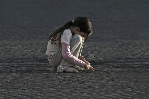 enfant fille seule recroquevillée sur la plage 