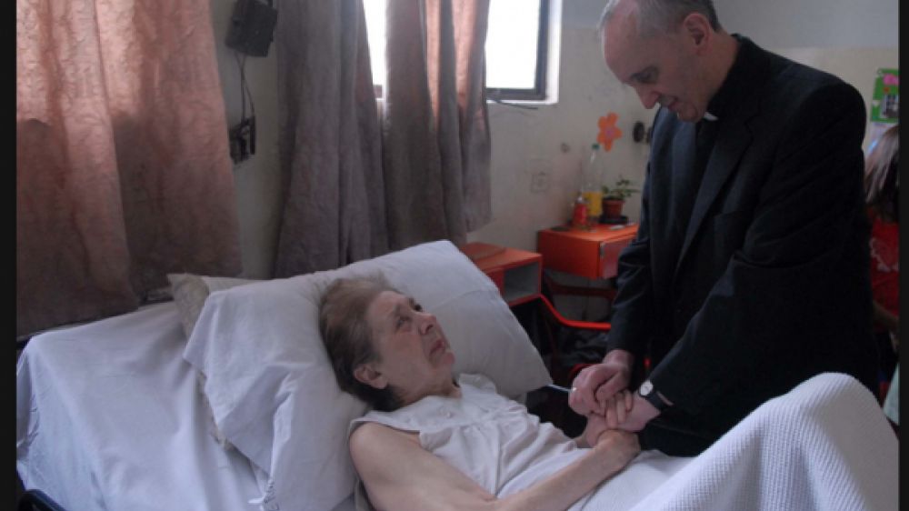 Jorge Mario Bergoglio, à l'hôpital de Buenos Aires (Argentine) priant aux côtés d'une dame âgée (2007).
